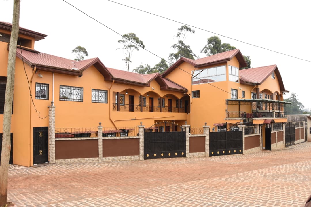Vue de l'Hôtel La Fraîcheur depuis la rue, avec portail et cour pavée