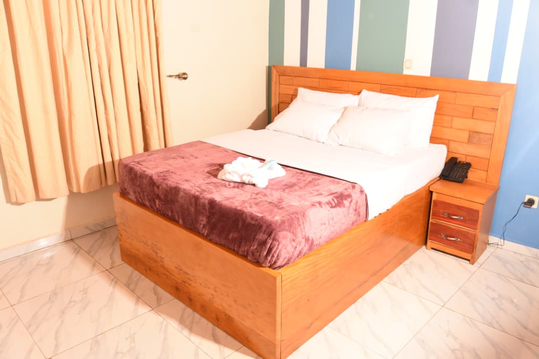 Chambre avec lit double, plaid bordeaux et mur rayé bleu
